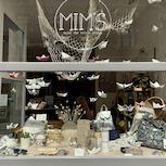 Vitrine Mim's avec bateaux en papier suspendus et articles variés