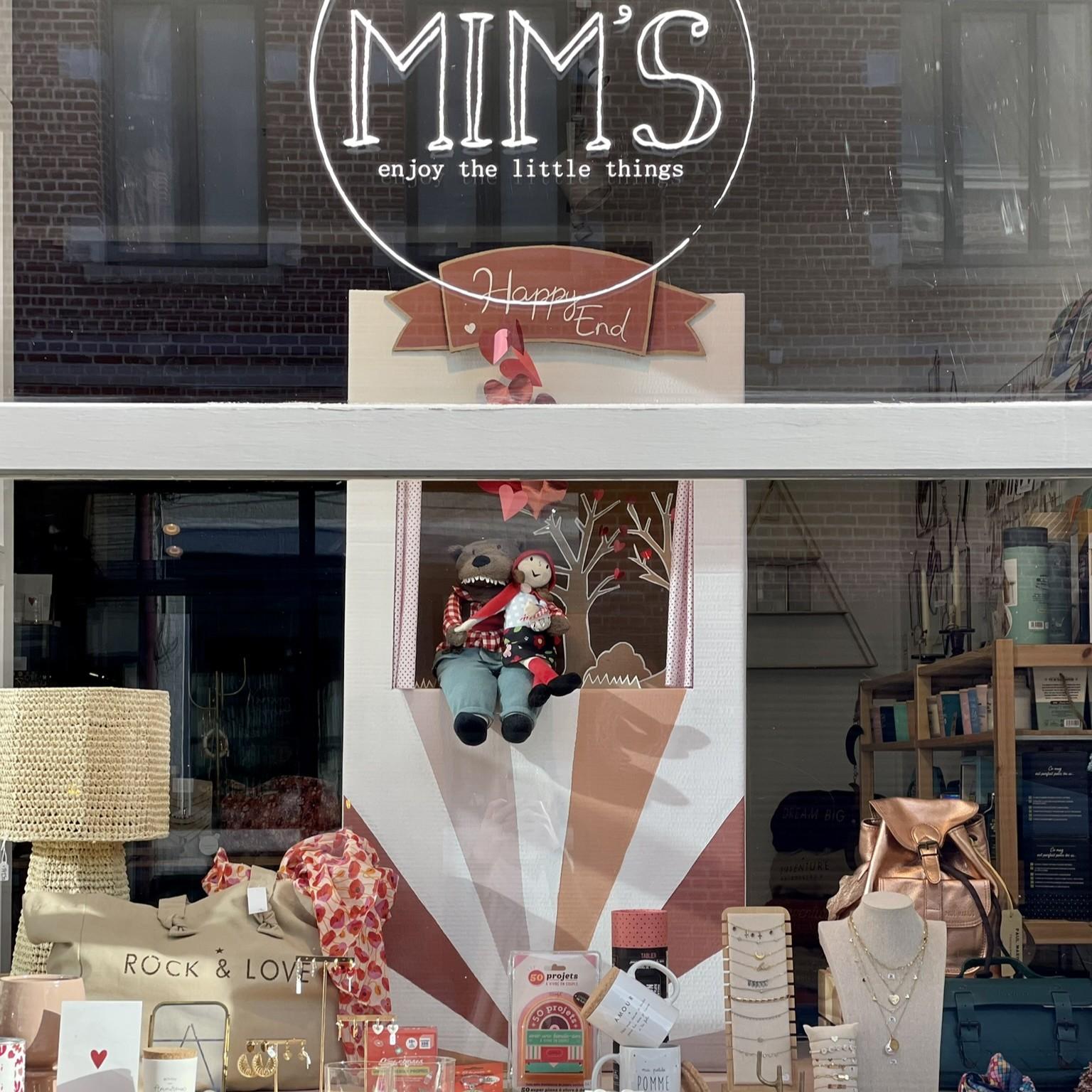 Vitrine de la boutique Mim's à Leuze-en-Hainaut représentant une scénette marionnette avec le Petit Chaperon Rouge et le Loup qui se font un câlin, dans une ambiance bordeaux avec sacs et bijoux