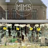Vitrine Mim's printanière avec fleurs blanches et jaunes, sacs verts, bijoux et déco