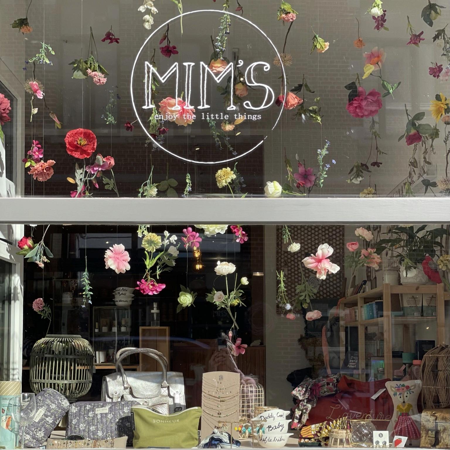 Vitrine de la boutique Mim's à Leuze-en-Hainaut avec de nombreuses fleurs séchées suspendues, créant une ambiance printanière