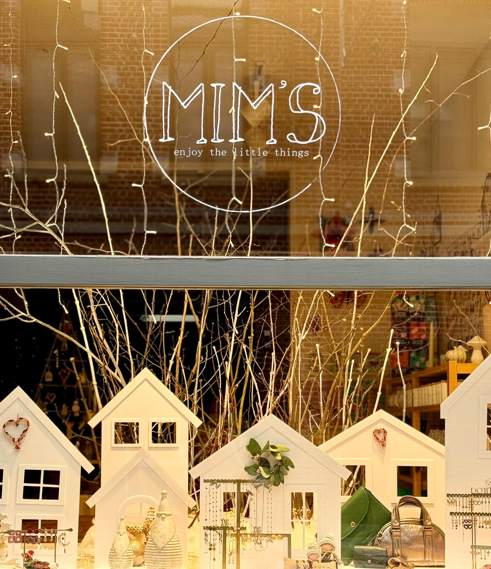 Vitrine de la boutique Mim's à Leuze présentant des petites maisons blanches en bois, des branches en arrière-plan, des sacs et objets fantaisie