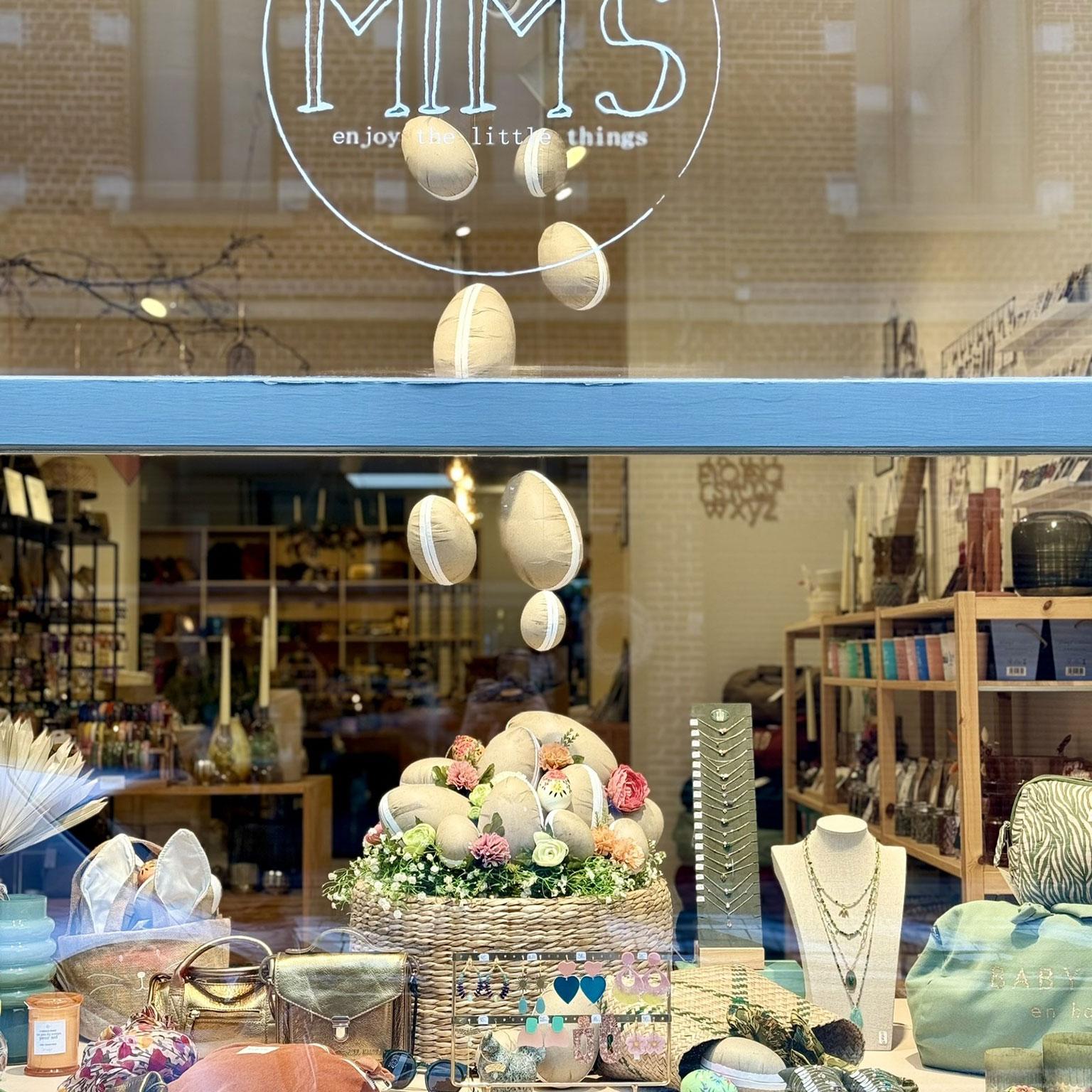 Vitrine de la boutique Mim's à Leuze décorée pour Pâques avec des œufs en tissu suspendus et dans un nid, des sacs et des bijoux dans des tons pastel